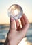 Woman`s hand holding Lemurian Clear Quartz Sphere at the sunrise