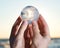 Woman`s hand holding Lemurian Clear Quartz Sphere at the sunrise