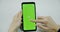 Woman`s hand holding a mobile telephone with a vertical green screen in tram chroma key smartphone technology cell phone