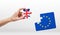 Woman\'s hand holding piece of jigsaw puzzle with European Union and Great Britain flag on white background