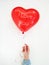 Woman`s hand holding a Red Heart balloon with inscription I Love