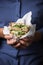 Woman`s hand holding a sandwich filled with fresh salad, cucumber and avocado.