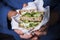 Woman`s hand holding a sandwich filled with fresh salad, cucumber and avocado.