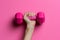 Woman& x27;s hand holding straight a bright pink dumbbell. Generative AI