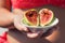 Woman`s hand holding a two ripe sliced figs. Female in the bright bikini with fresh sweet exotic fruit