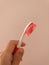 Woman's hand holding a used kids toothbrush red and white colors