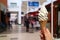 Woman`s hand holding vanilla milk soft serve ice cream cone in the sunlight