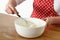 Woman`s hand holding whisk mixing cream cheese in bowl