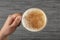 A woman`s hand is holding a white cup of hot milk drink with cinnamon called Turkish salep sahlep