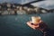 A woman`s hand is holding a white cup of hot milky beverage with cinnamon called Turkish salep sahlep on the background