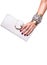 Woman`s hand holding a white leather clutch