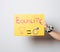 Woman\'s hand holding a yellow poster showing gender equality against the white wall