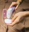 A woman`s hand holds a bottle of micellar water, a tonic cosmetic product with a cotton pad on a beige background