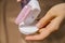 A woman`s hand holds a bottle of micellar water, a tonic cosmetic product with a cotton pad on a beige background