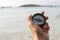 A woman`s hand holds a compass on the beach