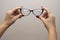 A woman`s hand holds glasses, selection of glasses to improve vision on a gray background, recommendations of ophthalmologists