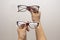 A woman`s hand holds glasses, selection of glasses to improve vision on a gray background, recommendations of ophthalmologists