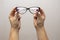 A woman`s hand holds glasses, selection of glasses to improve vision on a gray background, recommendations of ophthalmologists