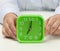 Woman`s hand holds a green square alarm clock, the clock shows seven in the morning. Wake up early, start the day