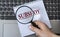 A woman`s hand holds a magnifying glass over the word SUBSIDY against the background of a laptop