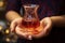 A woman\\\'s hand holds a pear shaped glass brimming with the rich, red goodness of Turkish tea
