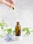 A woman`s hand holds a pipette with serum and drips into a bottle. Natural skin care concept. Essential oil