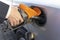 a woman& x27;s hand holds a refueling gun in the neck of the tank of the car. the girl refuels the car