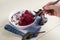 A woman's hand holds a spoon over a bowl of smoothies made of beetroot apples and raspberries.