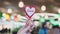 A woman's hand holds a symbol of love and romance on the backdrop of a public place in a restaurant. The