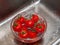 A woman`s hand holds tomatoes under running tap water, the importance of handling and thoroughly washing vegetables and fruits du