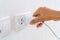 Woman`s Hand Inserting Electrical Power Cord Plug into Receptacle on wall outlet