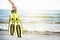 WomanÂ´s hand keep snorkel and swimming fins on a sandy beach. Water sports. Snorkeling. Travel and holiday concept.