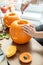 Woman`s hand with knife cuts pumpkin for Halloween