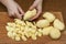Woman`s hand with a knife cutting slicing potatoes on wooden