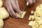 Woman`s hand with a knife cutting slicing potatoes on wooden boa