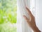 Woman`s hand opening curtains in the bedroom with natural light