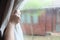 Woman`s hand opening curtains in the bedroom with rain droplet on the glass, natural light and blurred garden background with text