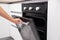 A woman`s hand opens the door of an electric convection oven. Built-in oven in the kitchen, energy consumption