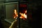 A woman\'s hand opens the glass door of the fireplace in which the wood is burning. Modern closed fireplace with glass