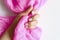 A woman`s hand with pale lilac painted nails holds a pink silk fabric isolated on a white background