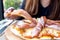 A woman`s hand picking a piece of Parma ham pizza up to eat in the restaurant