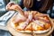 A woman`s hand picking a piece of Parma ham pizza up to eat in the restaurant