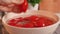 Woman\'s hand picks up ripe red tomato lying on sink with splashes of water in kitchen at home close-up. Natural