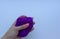 Woman`s hand with pink manicure holding a piece of violet wool on white background. Concept of felting creative hobby.