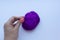 Woman`s hand with pink manicure sticking steel needle into the piece of violet wool on white background. Concept of felting creati