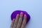 Woman`s hand with pink manicure touching a piece of violet wool on white background. Concept of felting creative hobby.