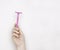 A woman`s hand with a pink shaving machine. Light background, free space for text