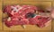 A woman`s hand pokes a piece of fresh beef with garlic and pepper on a chopping board with a fork