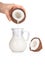 Woman\'s hand pouring coconut milk into a jar on white