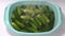 Woman`s hand pours the fresh cucumbers into the pelvis to prepare for homemade pickles